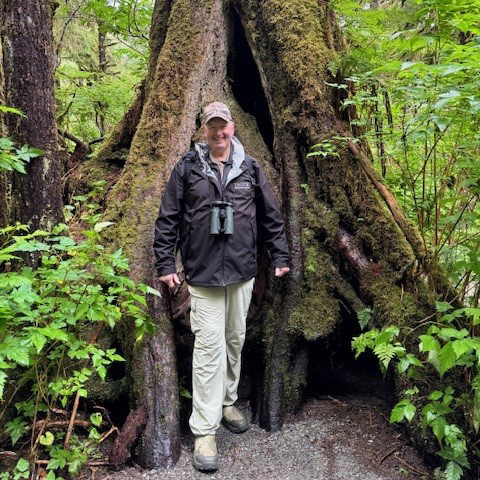 David Govatski stands in front of a giant tree.